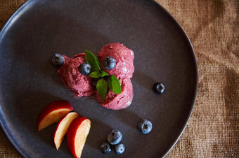 平躺生素食主义者甜点让人耳目一新蓝莓冰沙冰奶油片成熟的多汁的桃子薄荷叶子