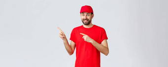 在线购物交付检疫外卖概念逗乐兴奋微笑快递邀请客户端员工红色的统一的帽t恤指出手指左