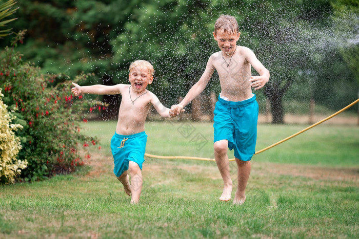 孩子们玩水热夏天一天孩子们花园喷水灭火系统户外有趣的男孩运行场水滴