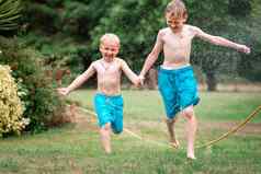 孩子们玩水热夏天一天孩子们花园喷水灭火系统户外有趣的男孩运行场水滴