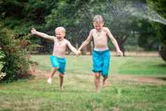 孩子们玩水热夏天一天孩子们花园喷水灭火系统户外有趣的男孩运行场水滴