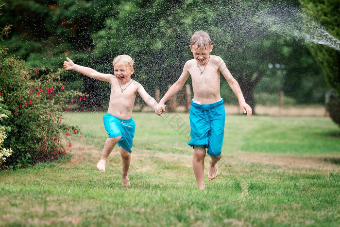 孩子们玩水热夏天一天孩子们花园喷水灭火系统户外有趣的男孩运行场水滴