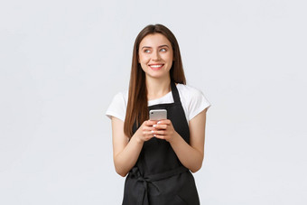 杂货店商店员工小业务咖啡商店概念微笑有吸引力的女服务员黑色的围裙笑左持有移动电话白色背景