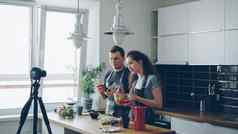 微笑有吸引力的夫妇记录视频食物视频博客烹饪海尔西沙拉数字相机厨房首页视频博客教育社会媒体概念
