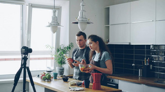 微笑有吸引力的夫妇记录视频食物视频博客烹饪海尔西沙拉数字相机厨房首页视频博客教育社会媒体概念