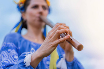 女人玩<strong>木</strong>管乐器<strong>木</strong>长<strong>笛</strong>乌克兰索皮尔卡在户外人音乐文化概念音乐的仪器夫人传统的绣花衬衫蓝色的维希万卡