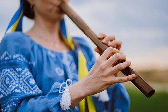 女人玩木管<strong>乐器</strong>木长笛乌克兰索皮尔卡在户外人<strong>音乐</strong>文化概念<strong>音乐</strong>的仪器夫人<strong>传统</strong>的绣花衬衫蓝色的维希万卡
