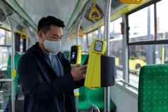 亚洲男人。公共运输公共汽车保护医疗面具购买电子机票电话