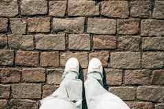 女腿牛仔裤白色运动鞋铺平道路石头十几岁的脚前视图布拉格街城市