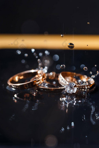 黄金婚礼环新婚夫妇婚礼一天黑色的背景水滴珠宝