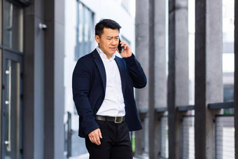 愤怒的成功的亚洲商人解释了信息员工电话