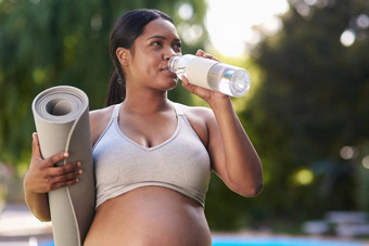 水合作用至关重要的你怀孕了怀孕了女人持有瑜伽席喝水站