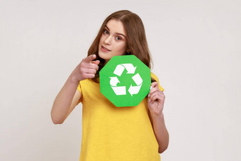 排序垃圾自信少年女孩黄色的休闲风格t恤持有回收标志指出手指相机令人担忧的环境