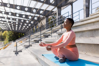 非洲美国女人执行呼吸练习坐着瑜伽席公园