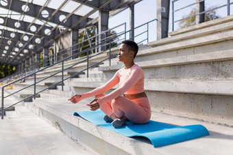 非洲美国女人执行呼吸练习坐着<strong>瑜伽</strong>席公园