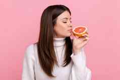 美丽的女闻一半片葡萄柚享受美味的维生素水果健康的营养