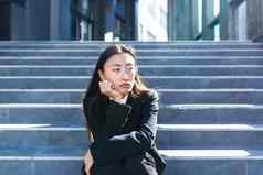 亚洲女人强大的头饰坐着楼梯生病的伤心抑郁女商人