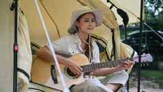 快乐女旅游坐着野营帐篷玩声吉他旅行冒险假期概念