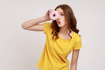 肖像积极的有趣的卷发少年女孩城市风格黄色的t恤甜甜圈使接吻手势有趣的