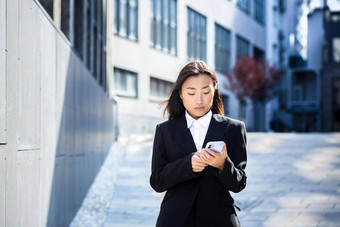 美丽的亚洲女人业务衣服电话走现代办公室