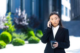 美丽的亚洲学生会说话的电话走大学校园
