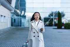 美丽的女旅游机场中国人女人走大手提箱