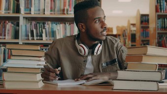 积极的非洲美国年轻的英俊的的家伙大耳机坐着表格书窗口微笑写作<strong>字帖</strong>