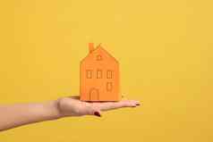 特写镜头女人手持有小橙色纸房子概念梦想首页购买抵押贷款