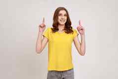 极快乐少年女孩棕色（的）波浪头发黄色的休闲t恤指出手指空空间满意广告区域