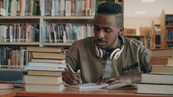 积极的非洲美国年轻的英俊的的家伙大耳机坐着表格书写作字帖