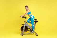 完整的长度金发女郎美丽的女人骑锻炼自行车健康的生活方式动机