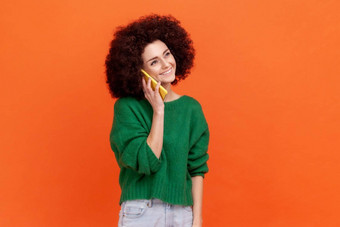 愉快的女人非洲式发型发型穿绿色休闲风格毛衣会说话的聪明的电话积极的面部表达式