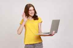 美丽的少年女孩波浪头发挥舞着手手势移动PC屏幕视频调用朋友沟通在线