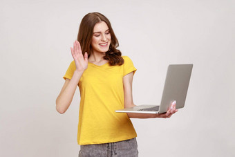 美丽的少年女孩波浪头发挥舞着手手势移动PC屏幕视频调用朋友沟通在线