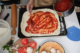 前视图过程准备披萨老板倒番茄酱汁滚面团新鲜的成分厨房表格