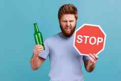 男人。蓝色的t恤显示含酒精的饮料啤酒瓶停止标志警告令人担忧的