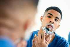 时间清洁剃集中年轻的男人。检查反射刮胡子脸