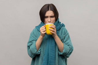 生病的不健康的女人围巾持有手杯热茶感觉发冷饮料热饮料