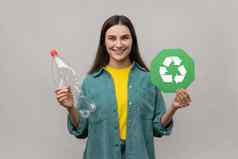 黑暗头发的女人可爱的微笑持有空塑料瓶绿色回收标志