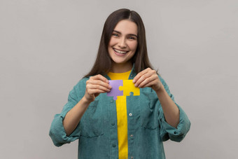 微笑快乐女人持有色彩斑斓的块谜题部分象征连接