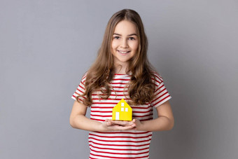 女孩持有纸房子微笑相机广告值得信赖的真正的房地产机构
