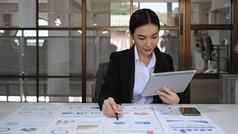 集中亚洲女商人分析股票图表数字平板电脑工作交易策略企业金融基金