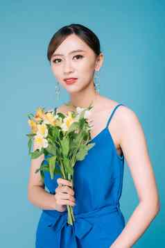 有吸引力的亚洲女人蓝色的衣服持有花束花蓝色的背景