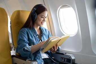 美丽的亚洲旅行女人阅读书<strong>飞机</strong>
