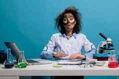 疯了愚蠢的科学家坐着桌子上实验室混乱的头发脏脸失败的化学实验