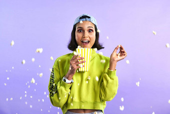 内核出现心停止行动包装电影工作室拍摄美丽的年轻的女人吃爆米花紫色的背景