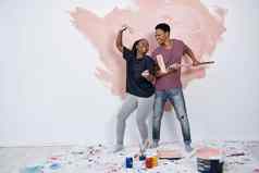 把油漆工作聚会，派对年轻的夫妇绘画墙粉红色的