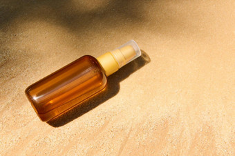 未打上烙印的黑暗瓶防晒系数石油防晒霜身体乳液金沙子海滩背景夏天化妆品概念