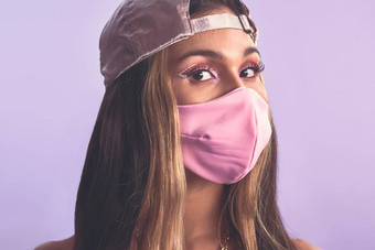 流行粉红色的工作室拍摄美丽的年轻的女人穿脸<strong>面具紫色</strong>的背景