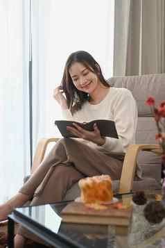 满意年轻的女人阅读书放松舒适的扶手椅首页休闲活动积极的情绪概念